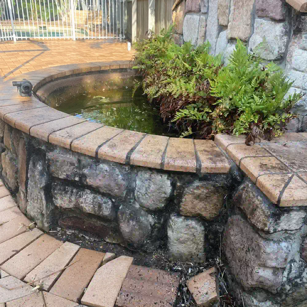 Dirty outdoor stone pond and paving before pressure cleaning with visible grime and buildup