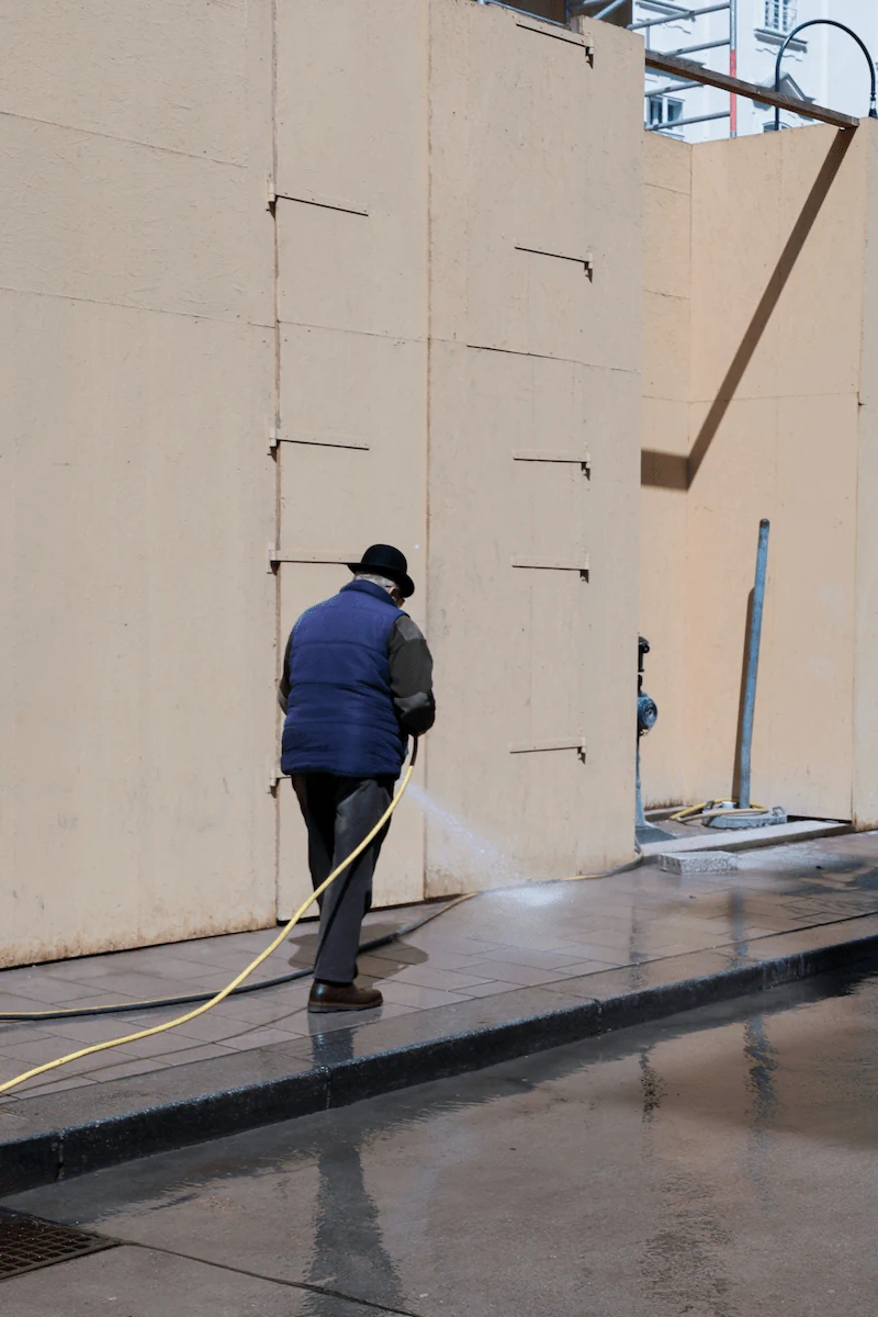 commercial-pressure-washing-building-wall-walkway Worker performing commercial pressure washing on exterior building wall and walkway